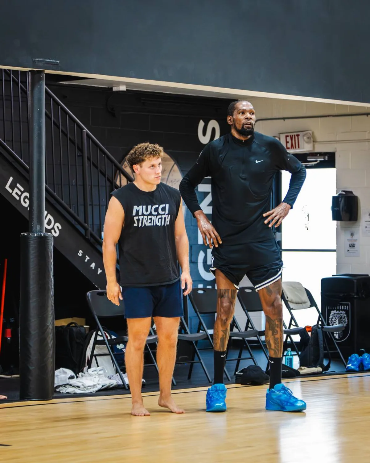 Justin Mucci in a Mucci Strength shirt beside an NBA player on a basketball court