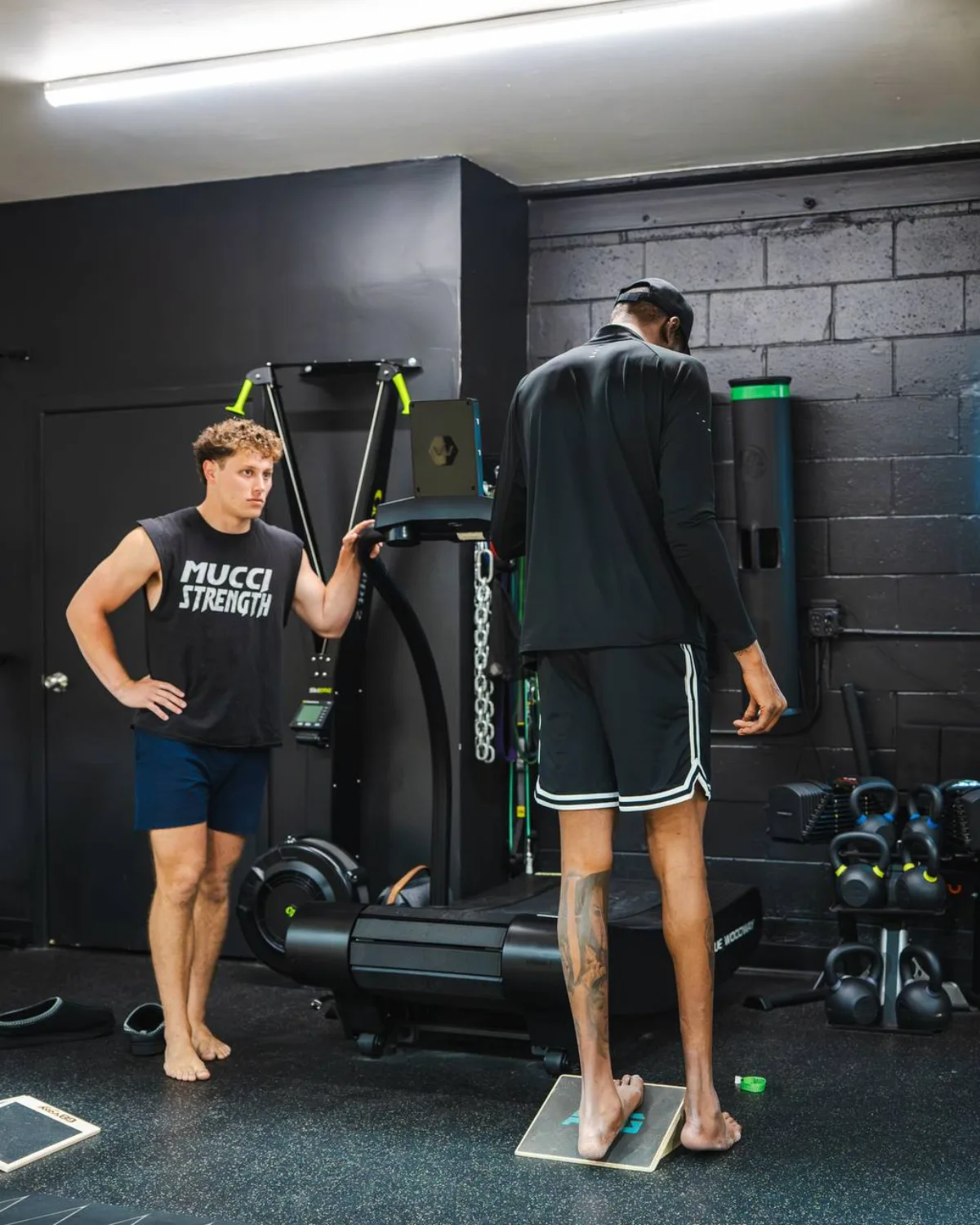 Justin Mucci watching an NBA player work on a slant board in the gym
